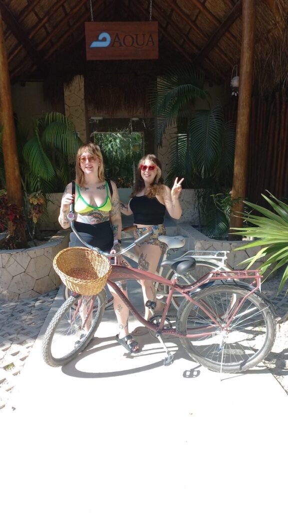 Two women standing outside a hotel with their rental bikes
